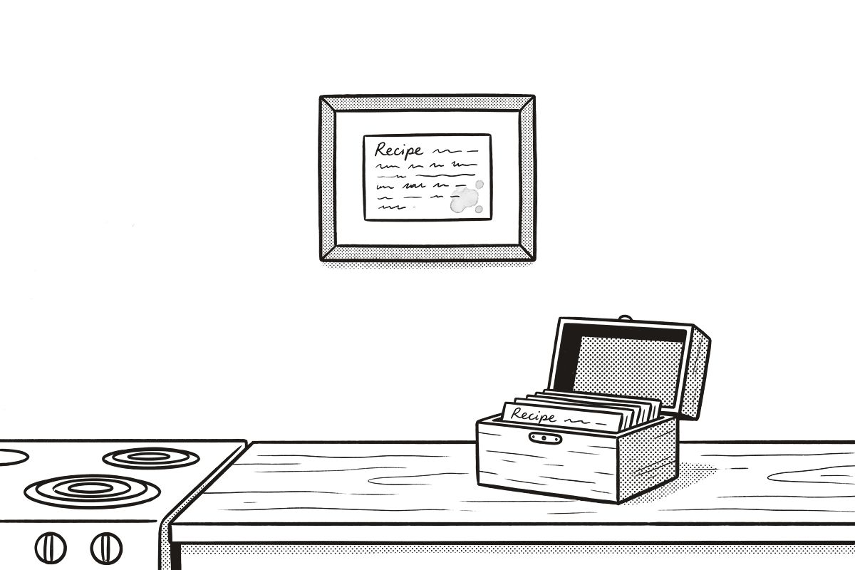 A framed recipe card on the wall beside the stove, an open recipe box on the counter below.