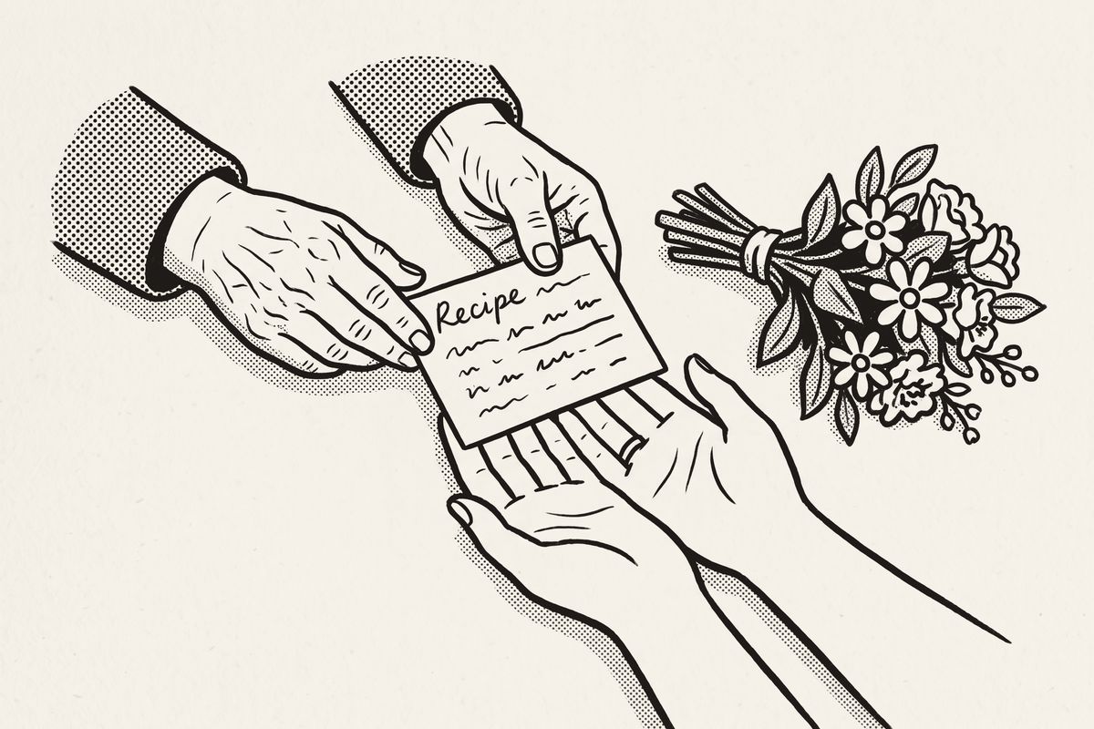 An older woman's hands passing a handwritten recipe card to a bride, beside a bouquet.