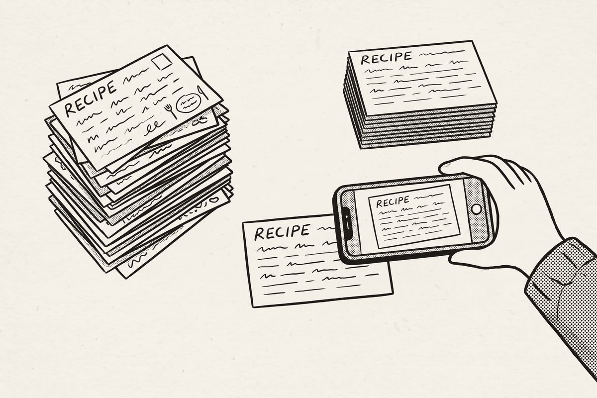 A stack of recipe cards, a hand photographing one, and a neat pile of finished cards.