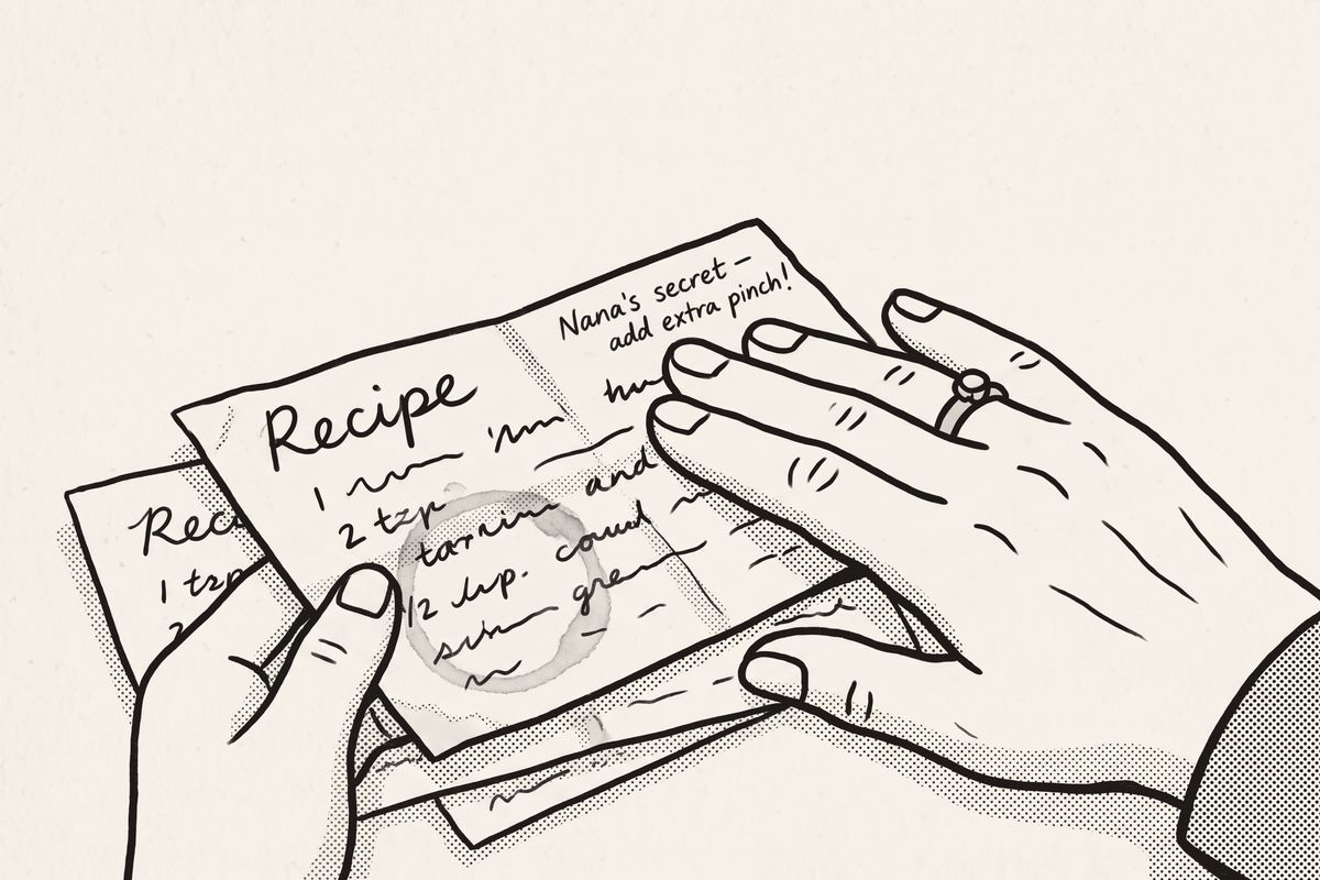 Two hands lifting one worn, stained recipe card out of a spread of cards.