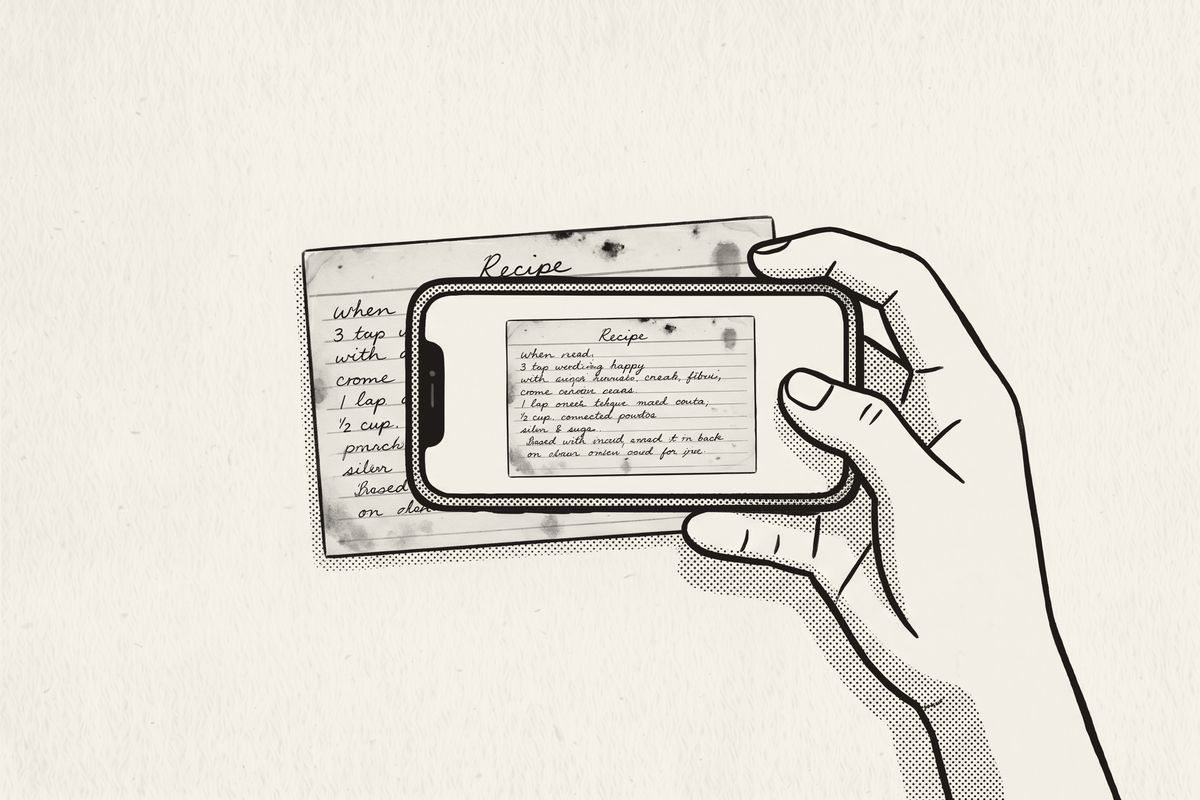 A hand holding a phone sideways over an old recipe card, the card on its screen.