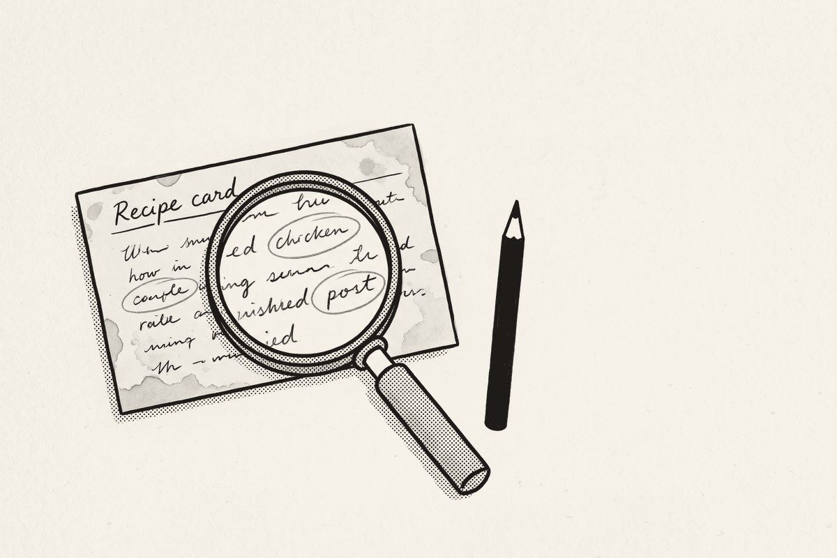 An old recipe card with words circled in pencil and a magnifying glass resting on it.