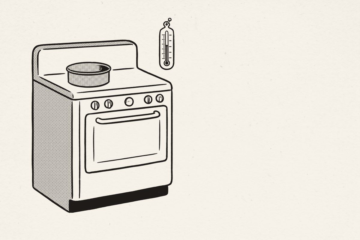 An old enamel kitchen range with unmarked knobs and a cake tin on top.