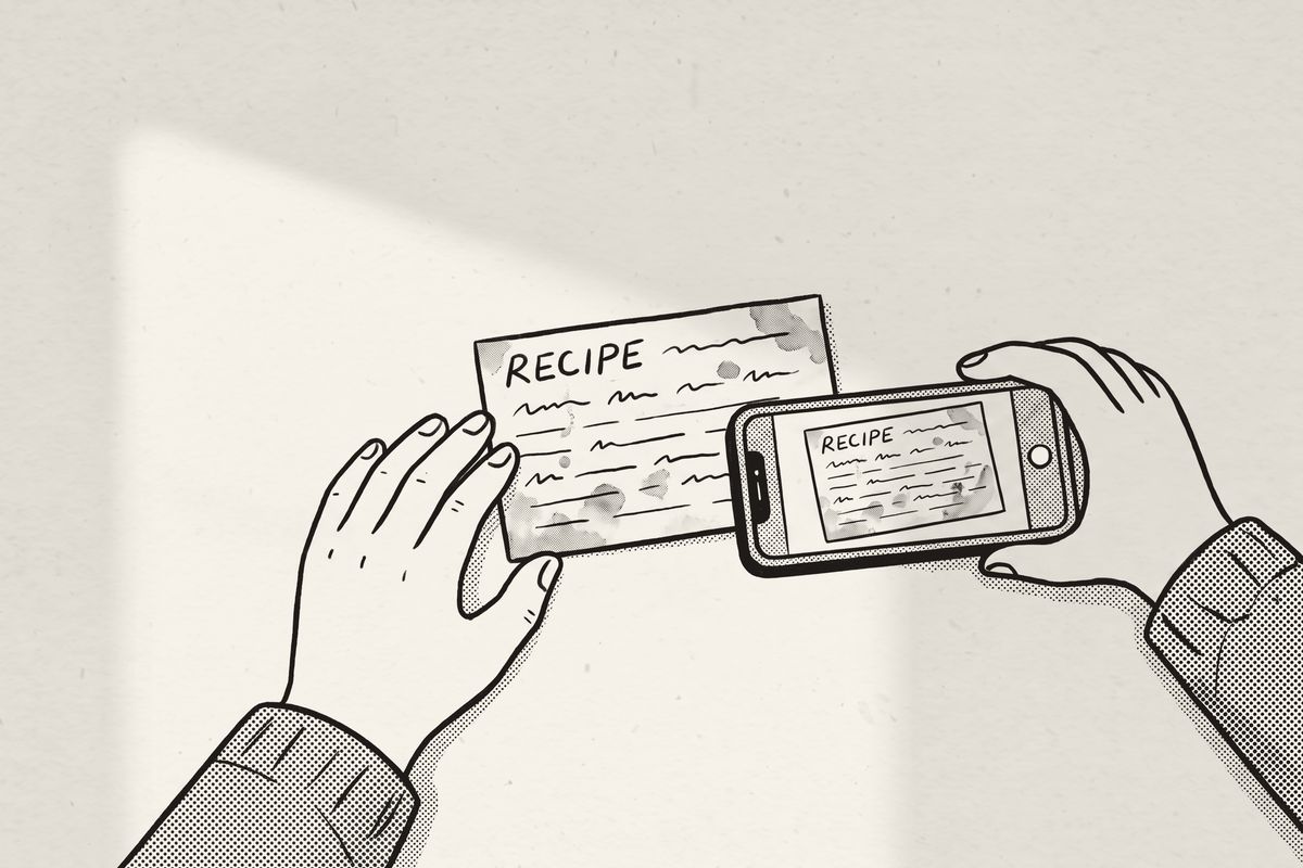 Two hands holding a phone steady over an old recipe card.
