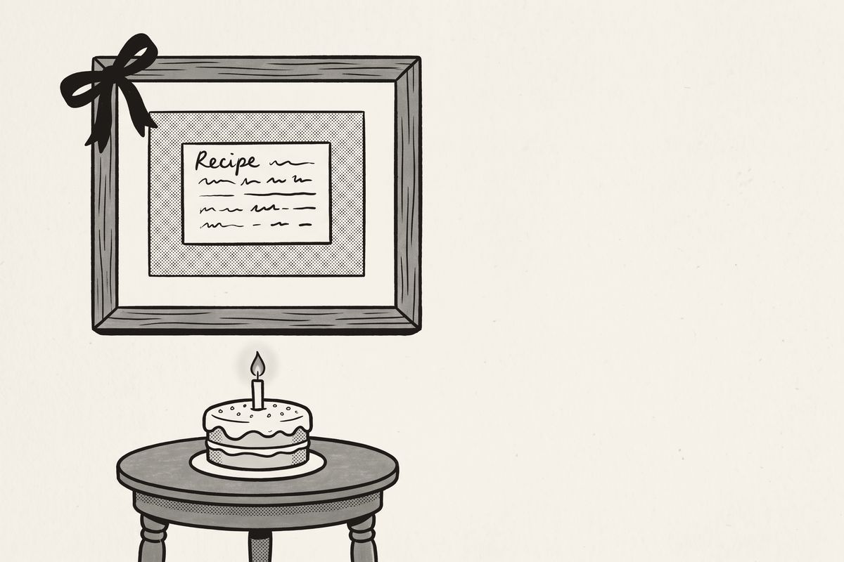 A framed recipe card with a ribbon bow on the wall, above a birthday cake with one candle.