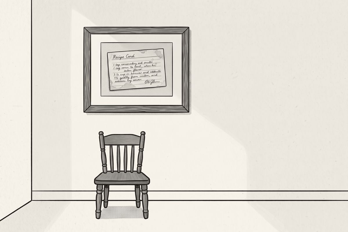 A framed recipe card on a quiet hallway wall, a small chair below it.