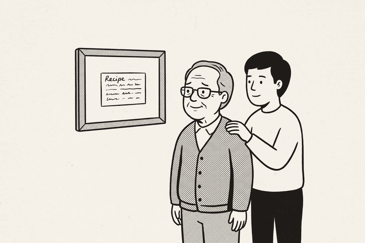 A father and his grown son looking at a framed recipe card on the wall.