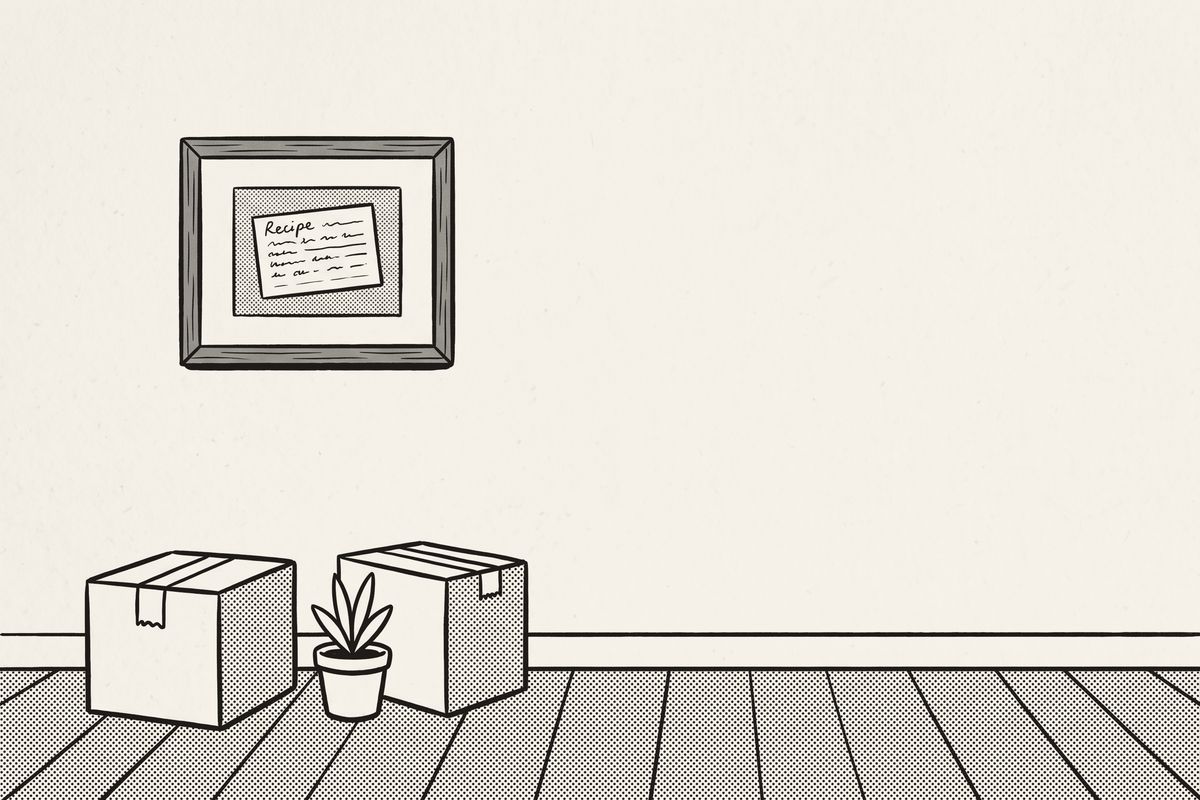 A framed recipe card on the wall of a new home, above moving boxes and a plant.