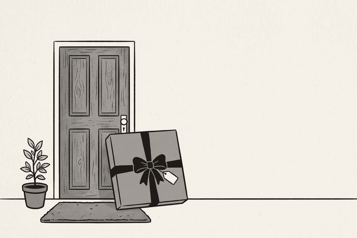 A wrapped flat gift with a ribbon leaning against the front door of a new home.
