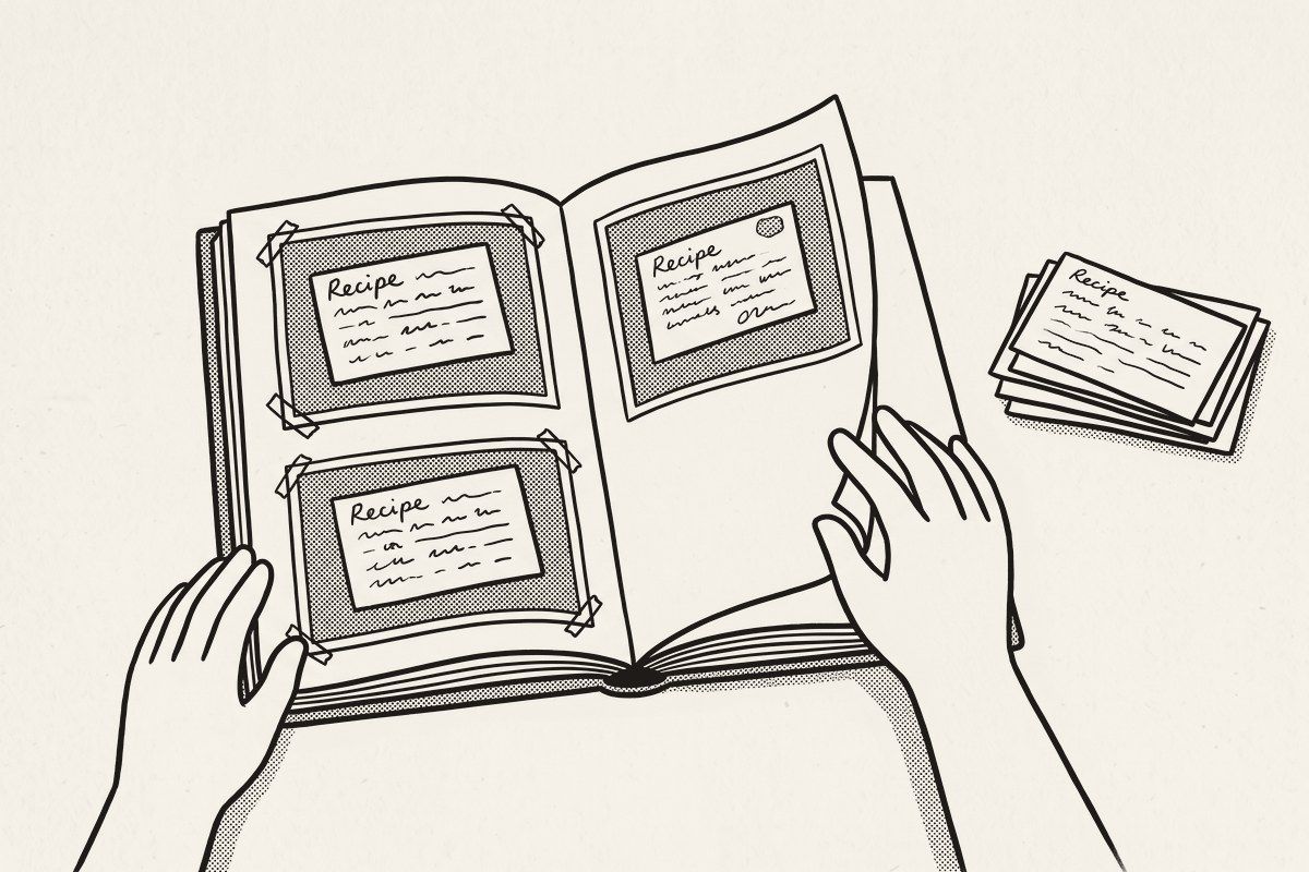 Two hands turning the pages of a homemade family cookbook full of recipe cards.
