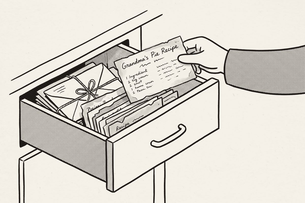 A hand lifting one recipe card out of a drawer full of old cards.